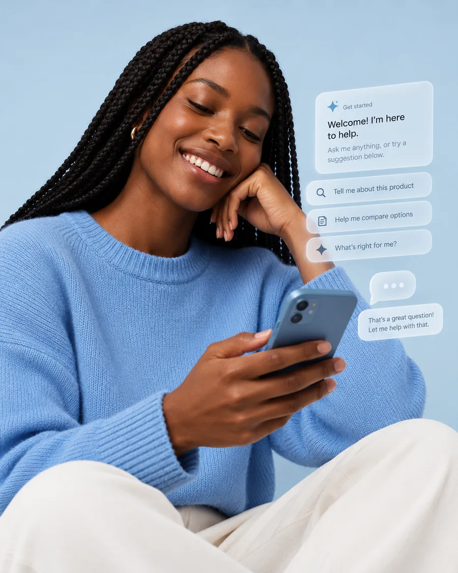 A woman in a blue sweater smiling at her phone, a chat assistant interface beside her